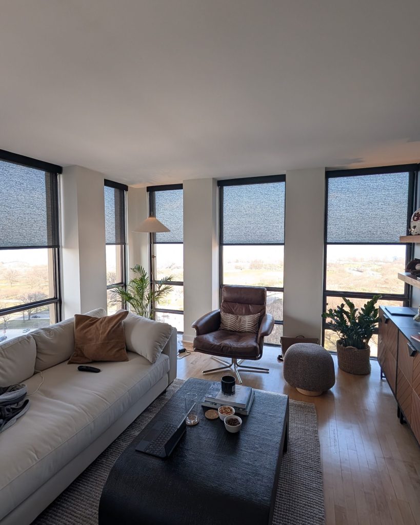 Chicago Blinds and Shades roller solar shades Chicago old town black ยป Chicago Blinds and Shades ยป Chicago Blinds and Shades Bright living room with large windows, beige sofa, brown leather chair, plants, and a coffee table with snacks on it